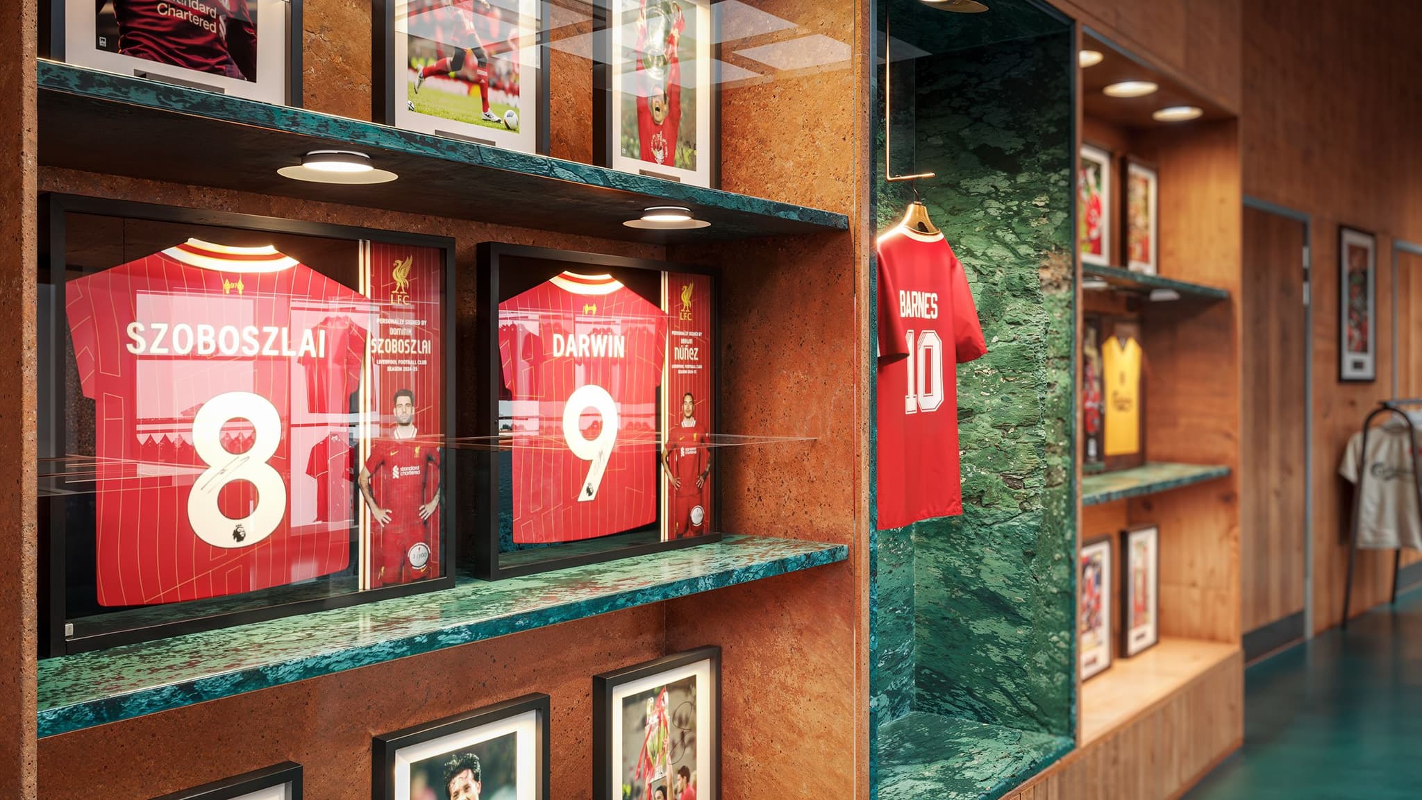 Framed signed Liverpool FC jerseys of Szoboszlai and Darwin, alongside a retro Barnes shirt, displayed on a store wall.