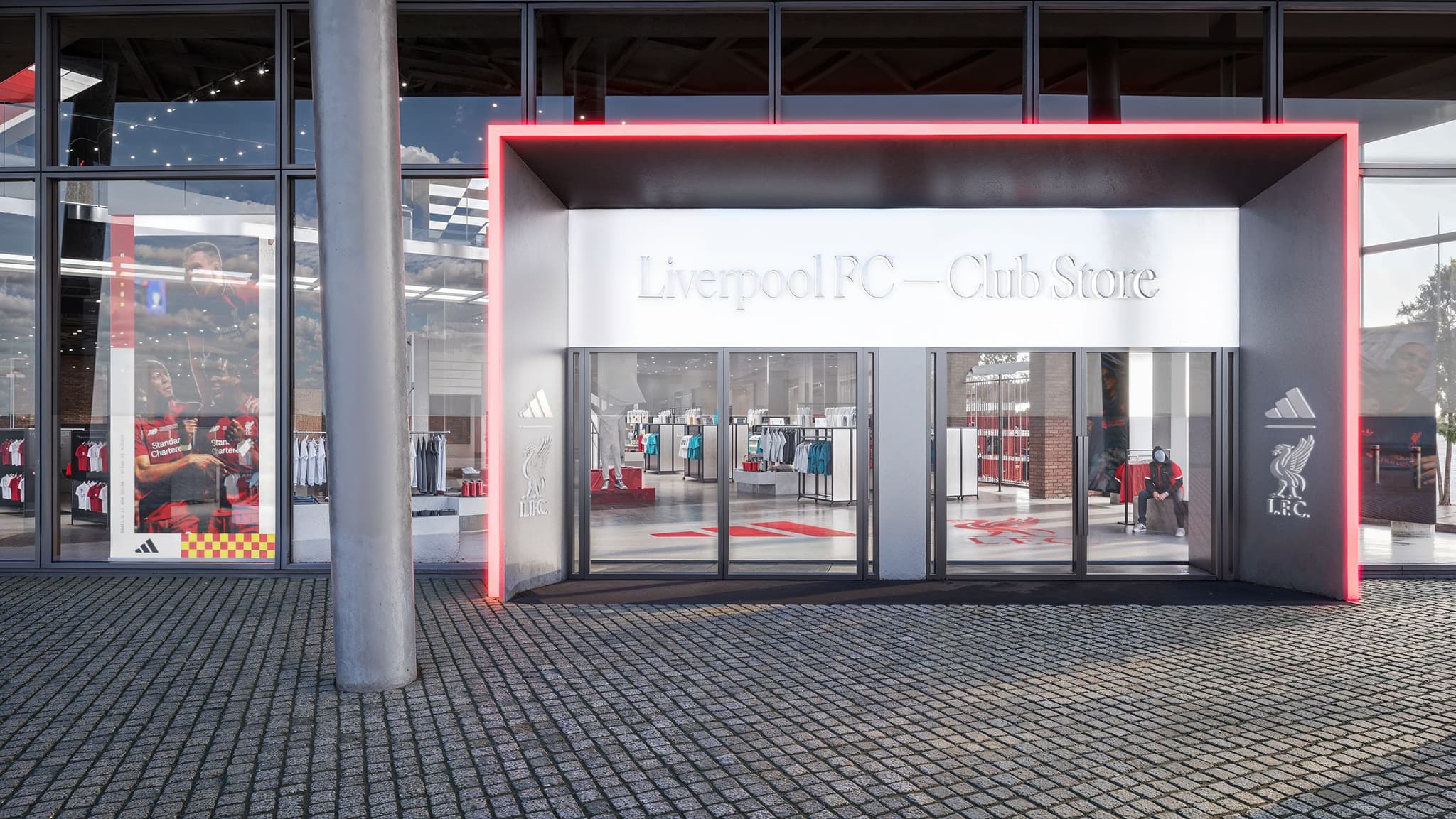 Exterior entrance of the Liverpool FC Club Store with glass doors, illuminated signage, and a neon red border.