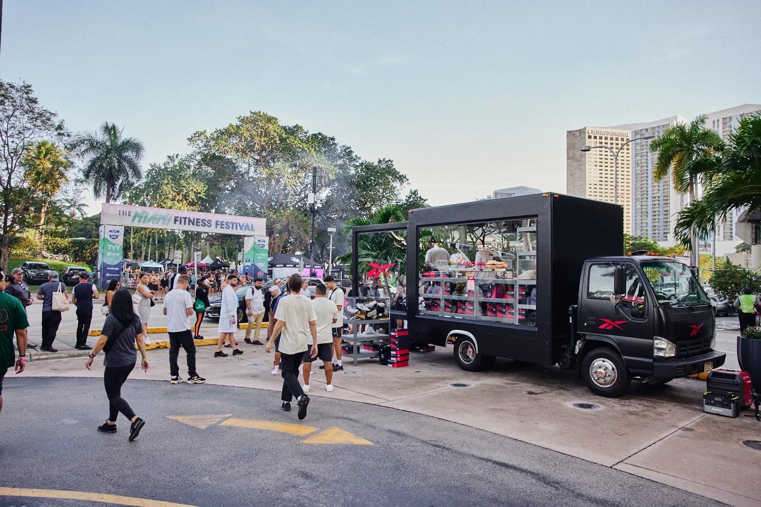 Wide view of the Reebok activation truck parked at the Miami Fitness Festival with attendees walking by.