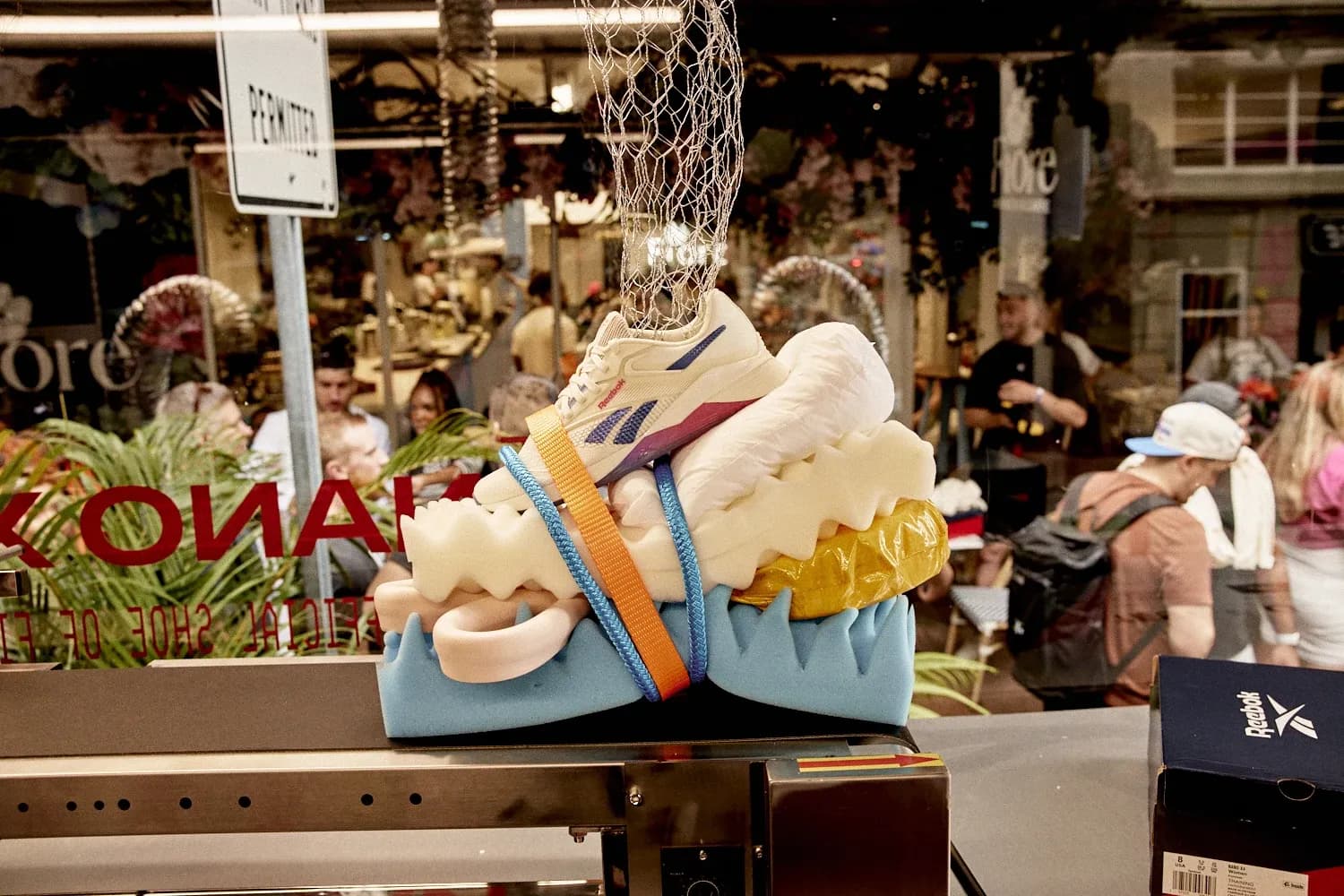 Reebok Nano X4 sneaker displayed on a stack of colorful foam and sponges inside a glass-walled truck.