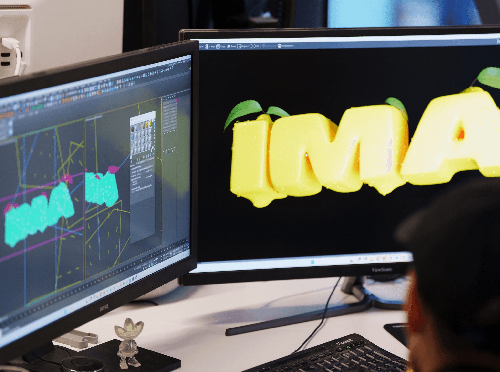 Close-up of dual computer monitors displaying graphic design and video editing software in a dark studio.