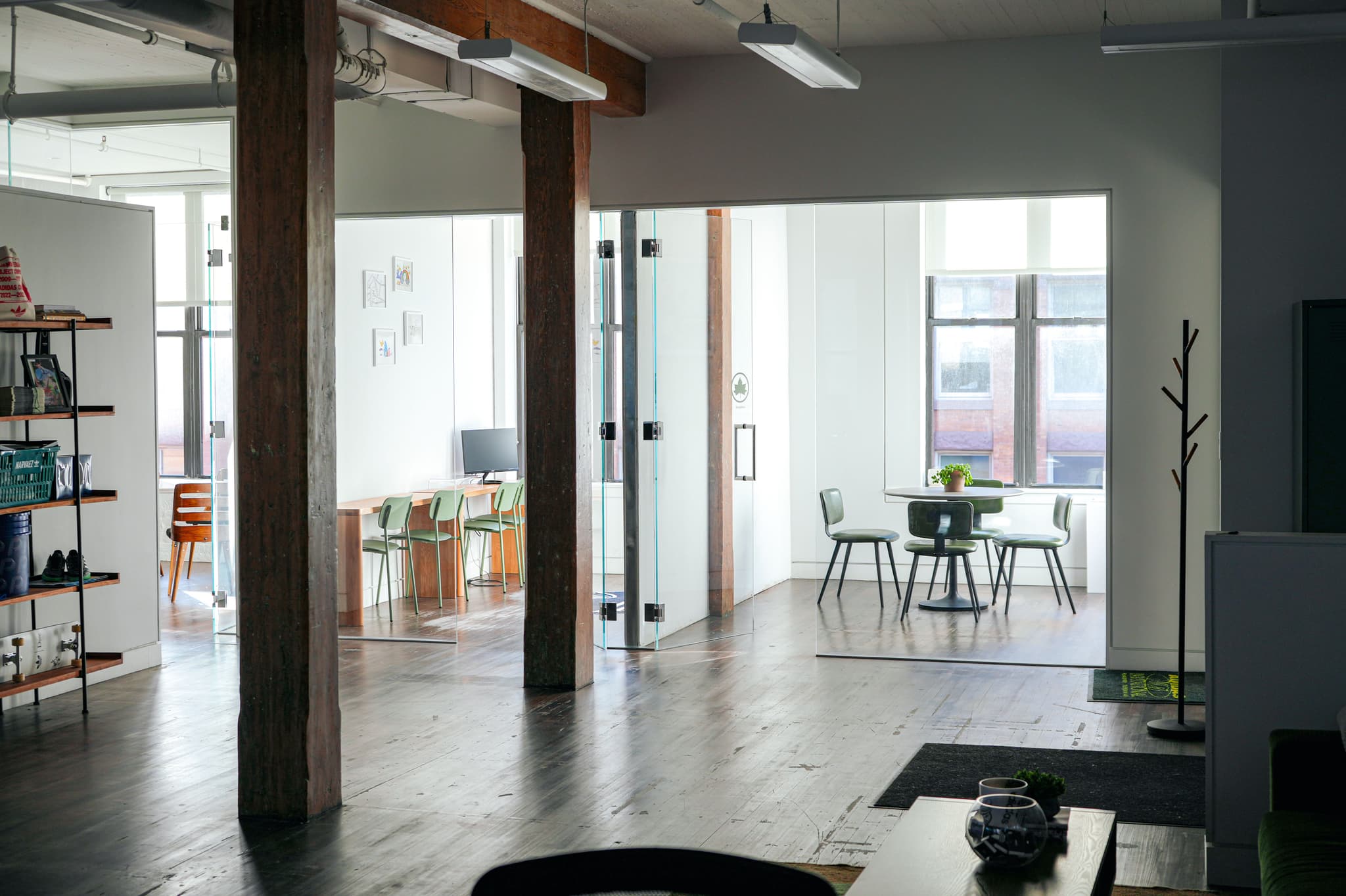 Open-plan workspace at the IMA New York office featuring wooden pillars and glass meeting rooms.