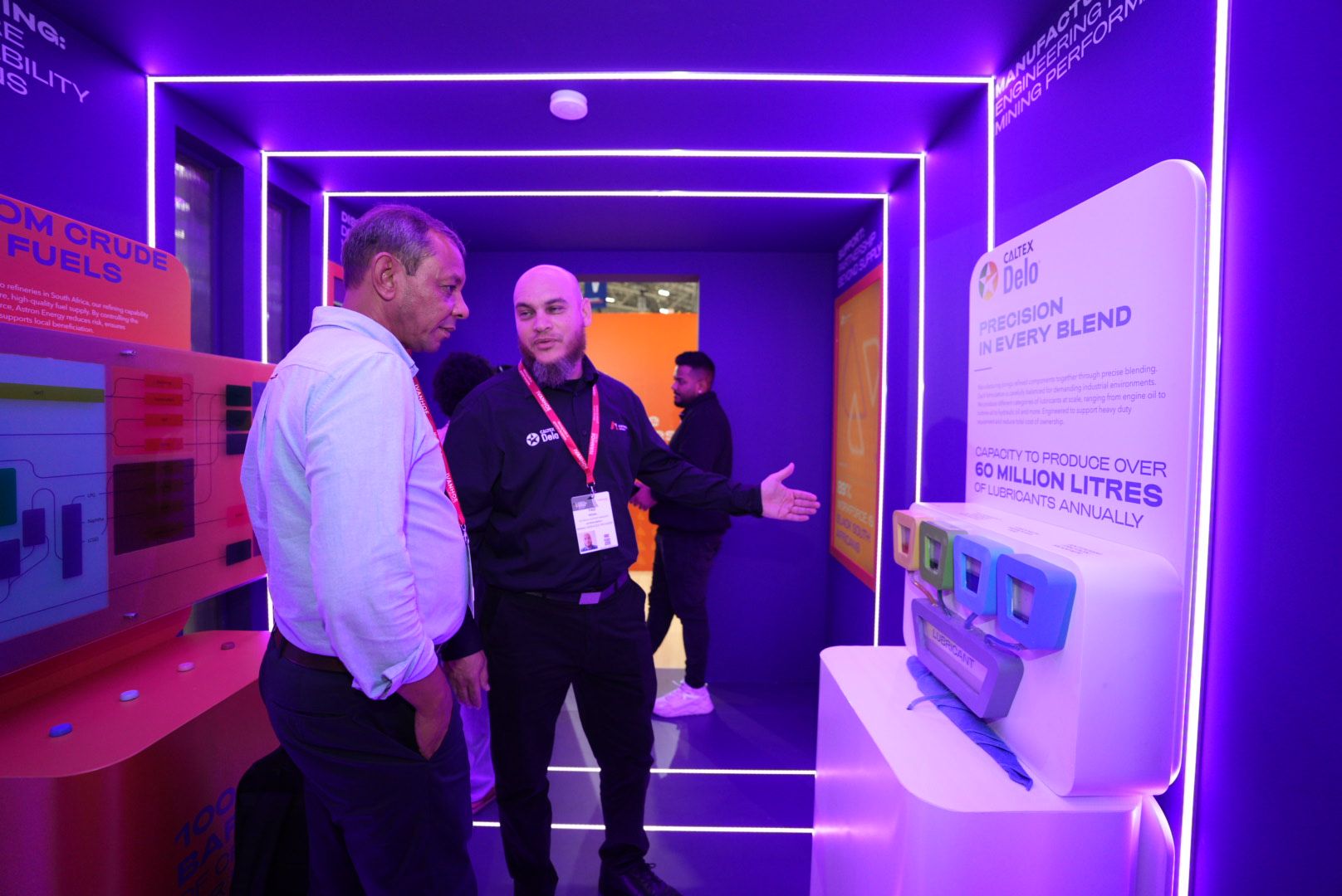Two men looking at a Caltex Delo interactive display inside the purple neon-lit Astron Energy tunnel.