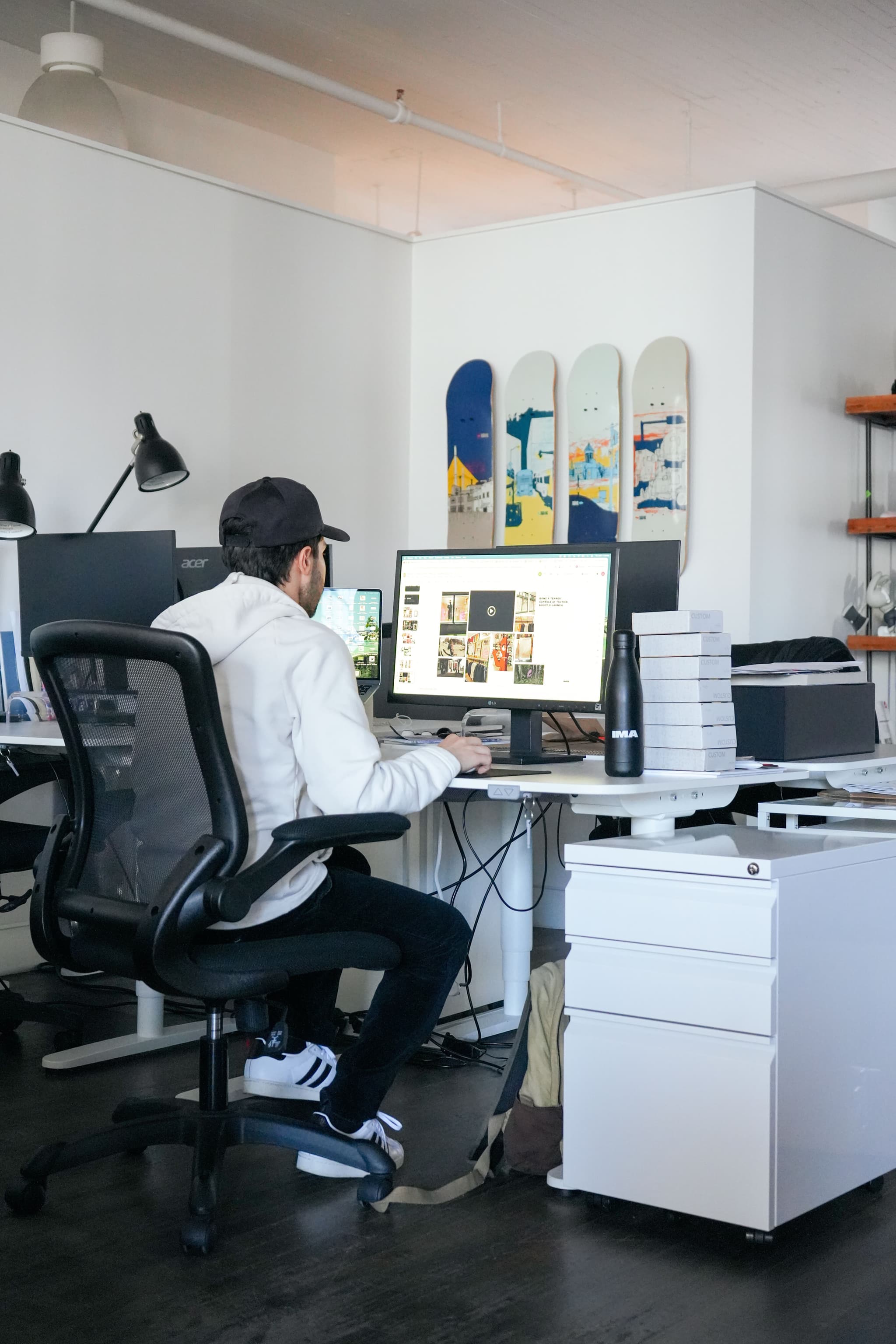 Employee working at a dual-monitor desk with skateboards on the wall in the IMA New York office.