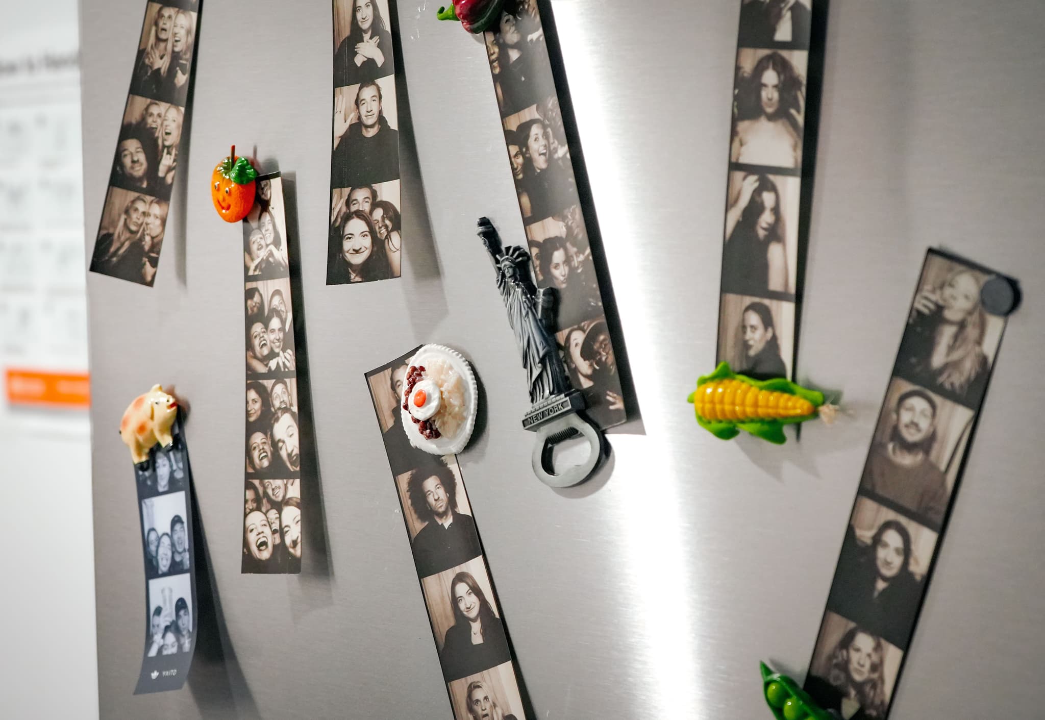 Stainless steel office refrigerator decorated with photo booth strips and quirky magnets.