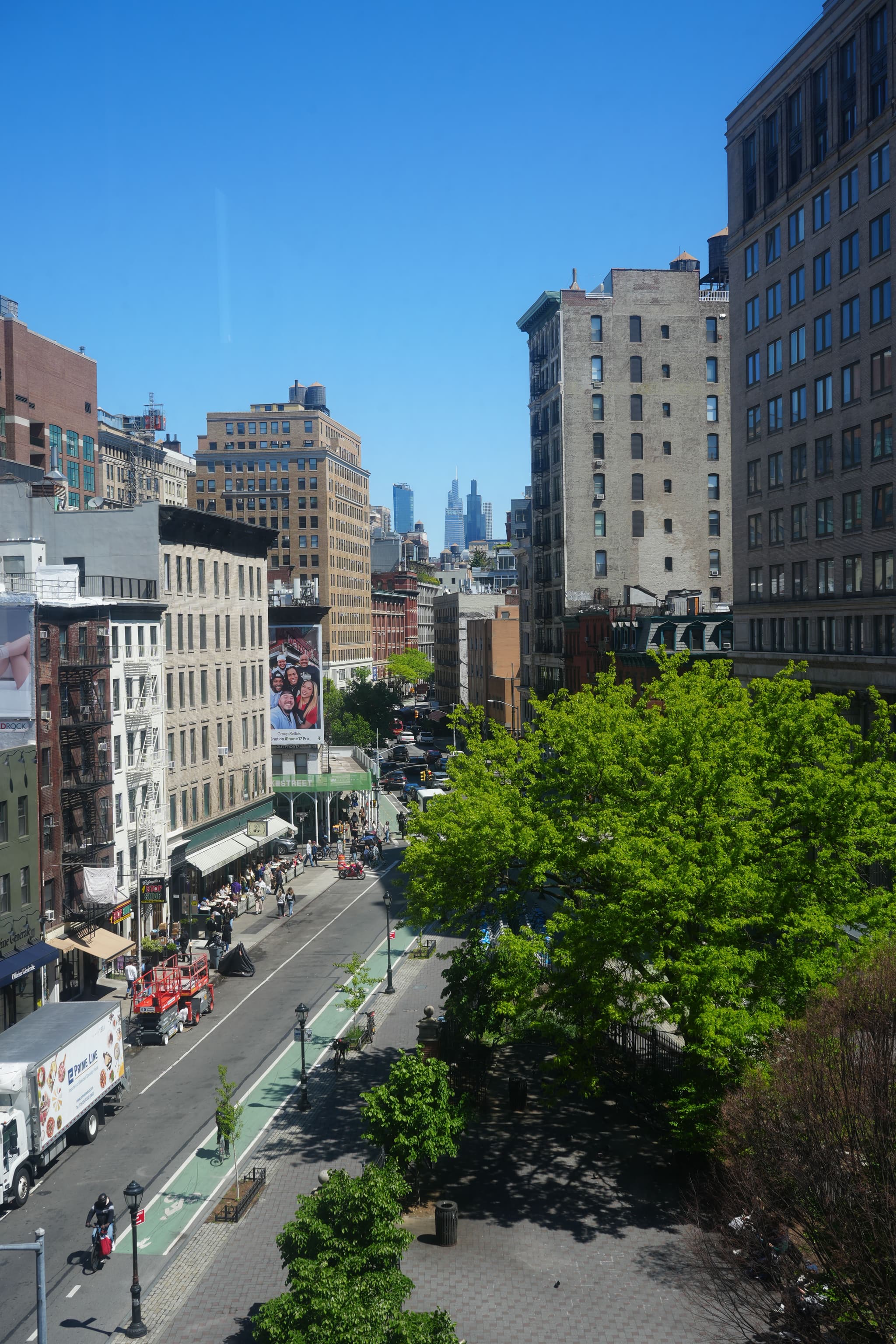 High-angle view from the IMA New York office looking down a busy city street with bike lanes, trees, and tall buildings.