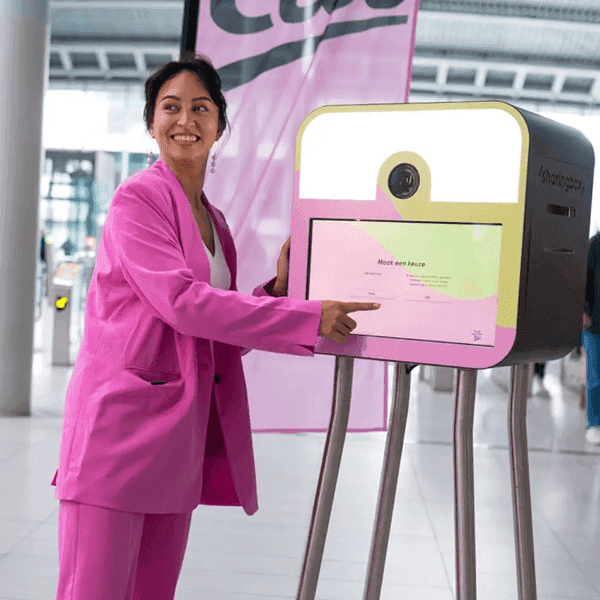 Woman in a pink suit using a branded digital touchscreen interface at an Etos event.