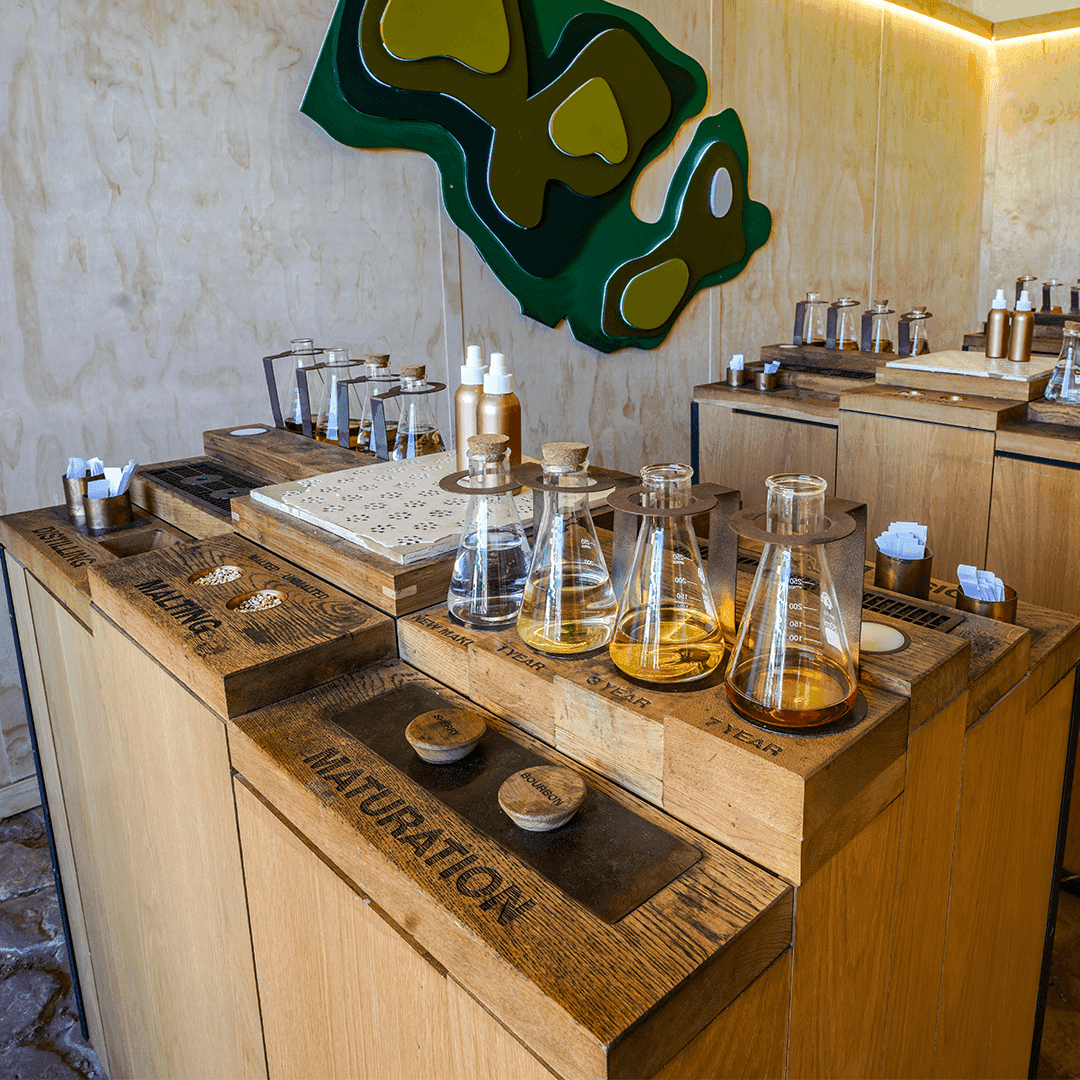 A wooden display detailing the Jameson whiskey distilling process, featuring beakers showing malting and maturation stages.
