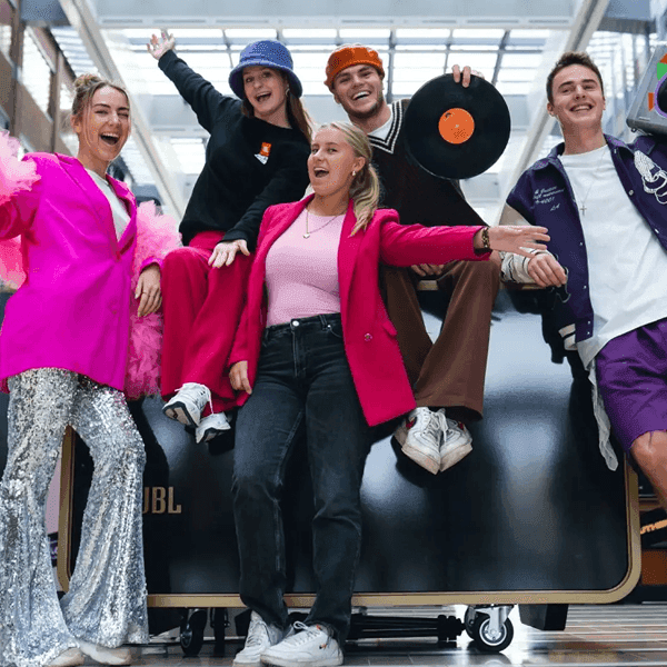 Energetic group posing with vinyl records at a JBL promotional photo booth event.