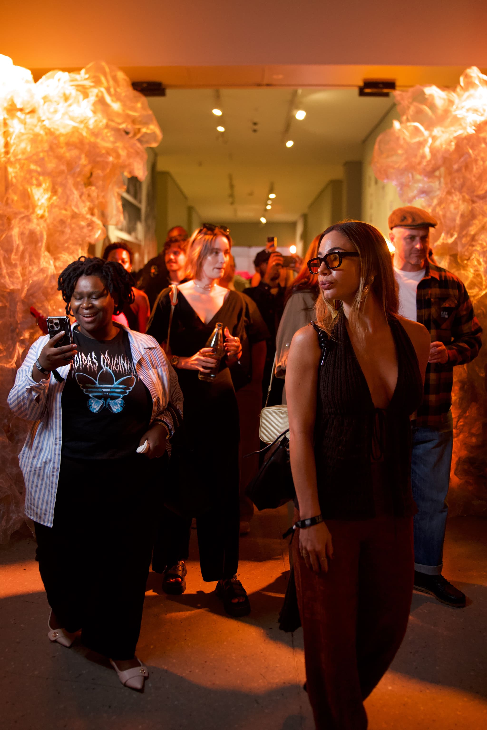 Attendees walking through a warm, orange-lit event hallway featuring cloud-like decorative installations.