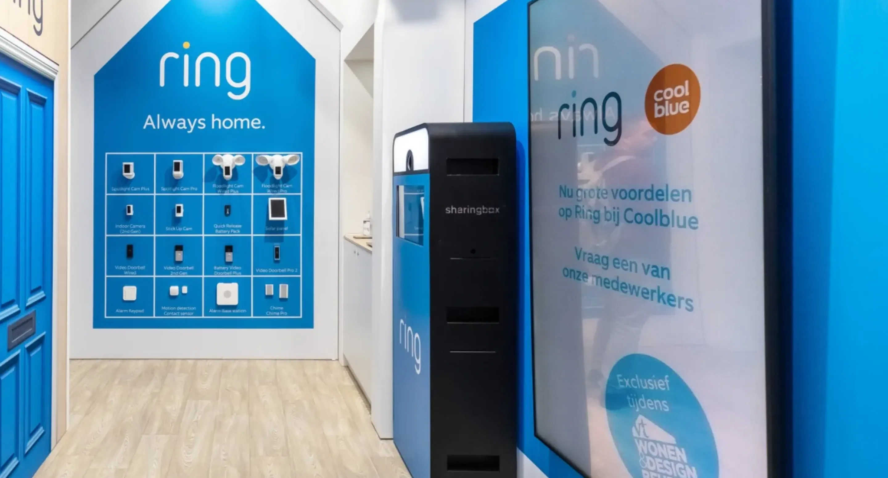 Wall display of Ring security cameras and doorbells under the slogan "Always home" next to a digital kiosk.