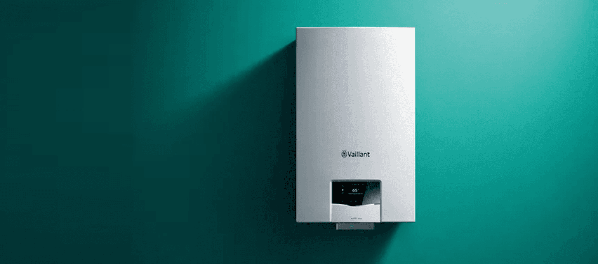 White Vaillant wall-mounted boiler unit with a digital display mounted on a dark green wall.
