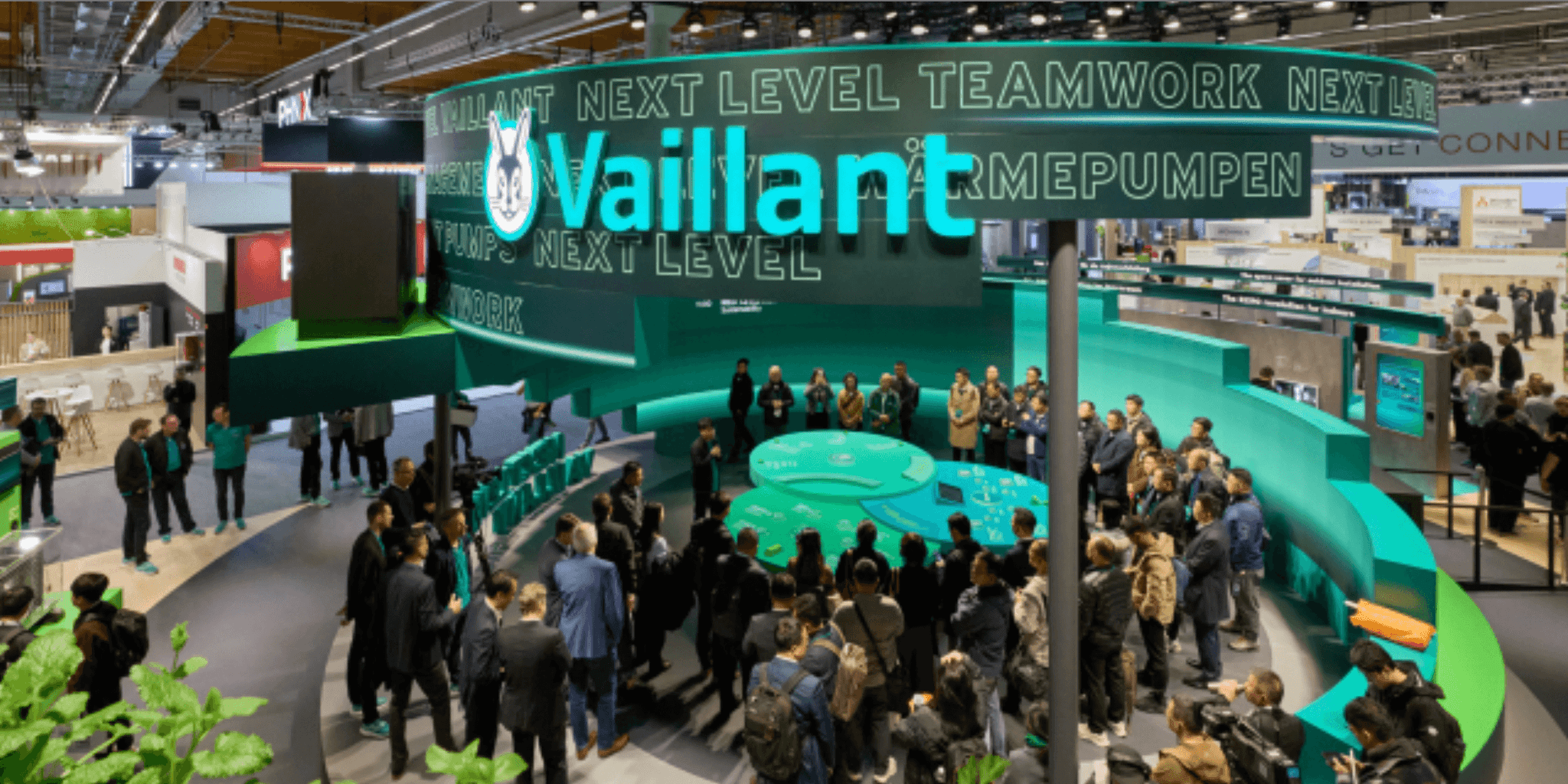 Large green Vaillant exhibition stand surrounded by a crowd at a trade show, featuring Next Level Teamwork branding.