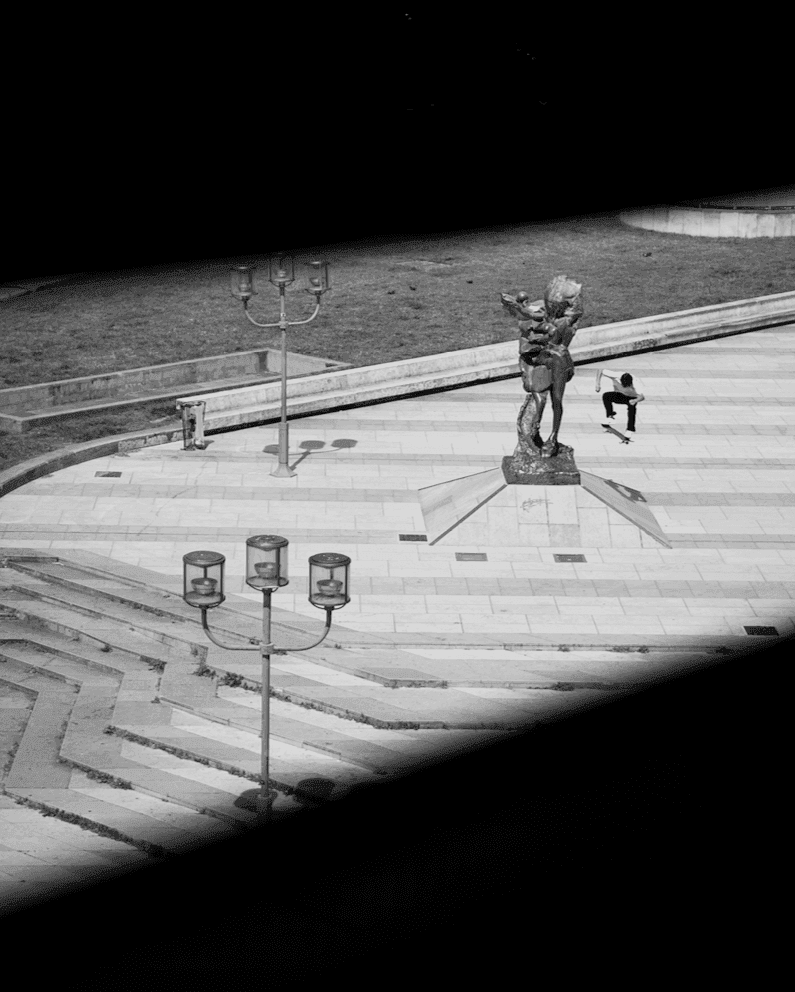 Black and white photograph of a skateboarder performing a trick in stadium