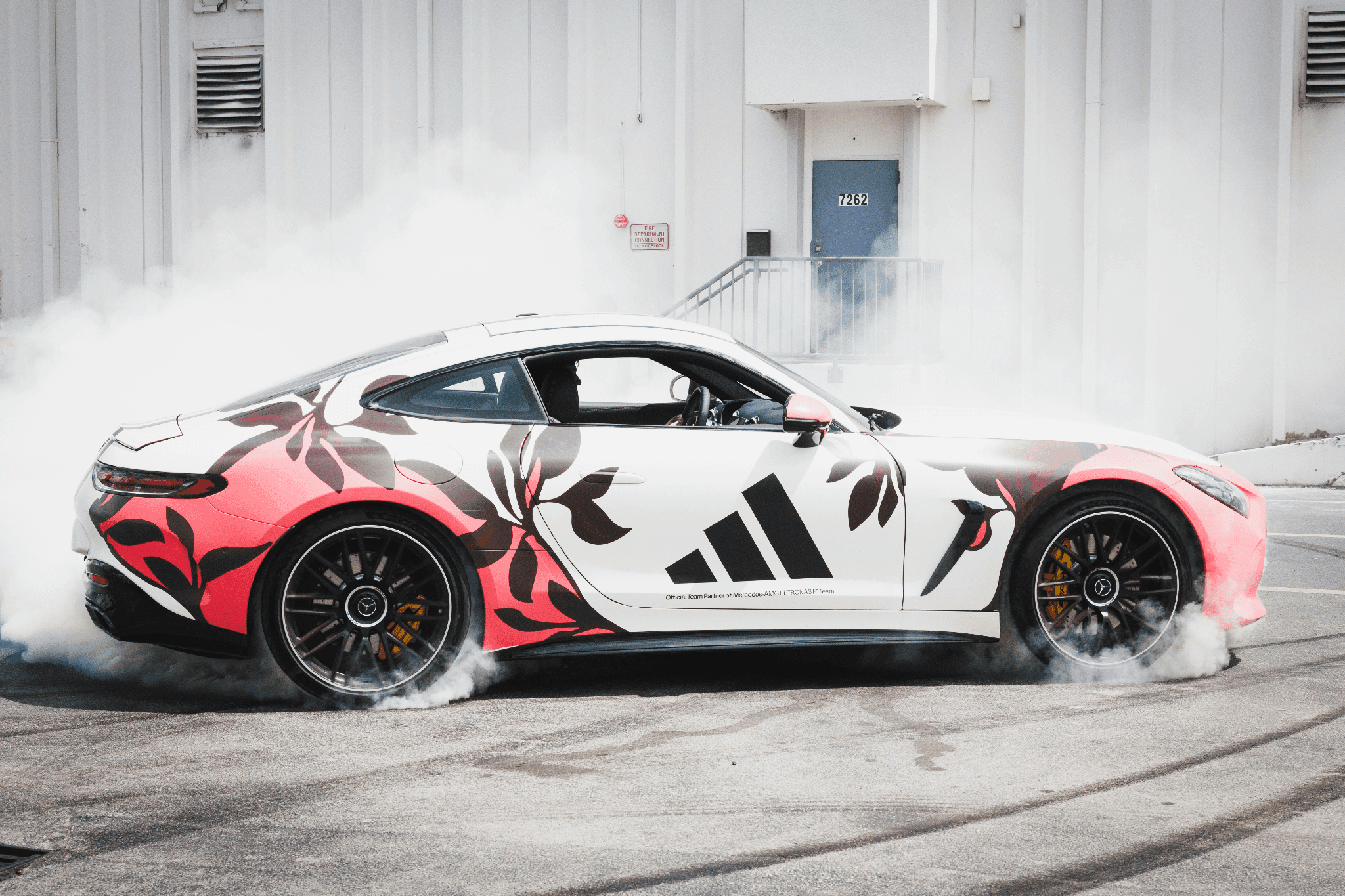 A Mercedes-AMG F1 car drifting and creating tire smoke during the Adidas Skateboarding PR event.