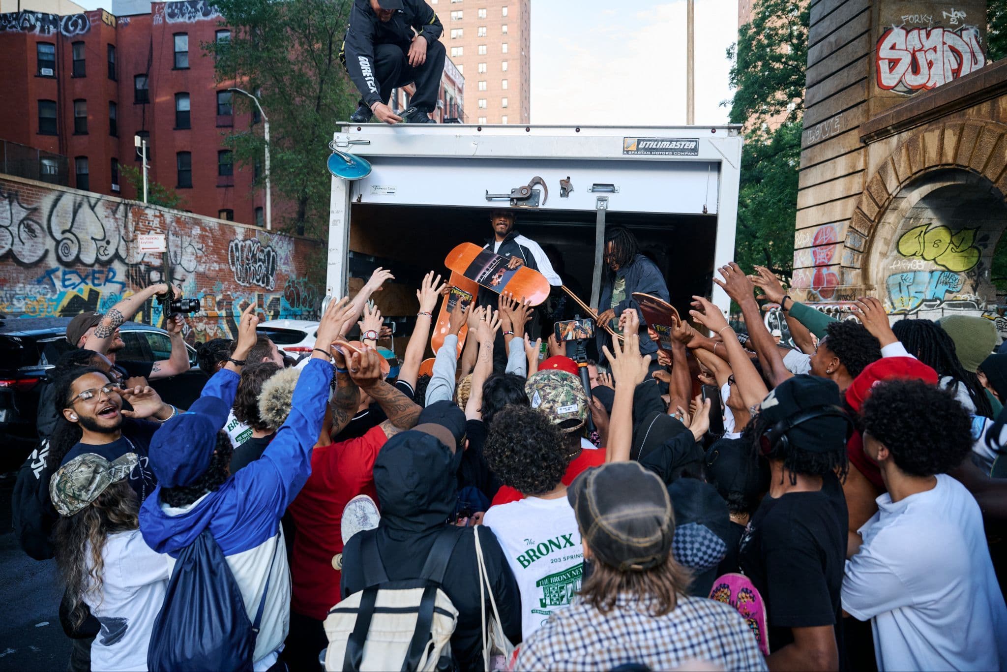 A large, energetic crowd raising their hands toward the back of an open delivery truck.