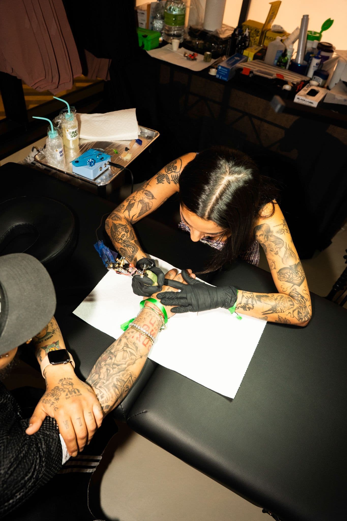 High-angle shot of a person getting a tattoo on their arm from a professional artist.