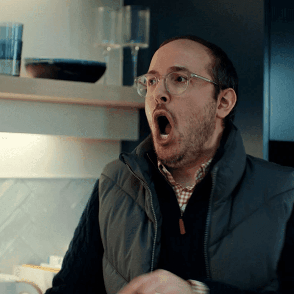 A man with glasses looking extremely shocked with his mouth wide open in a kitchen setting.