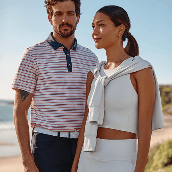 A man and woman in athletic summer wear standing together in a scenic outdoor location.