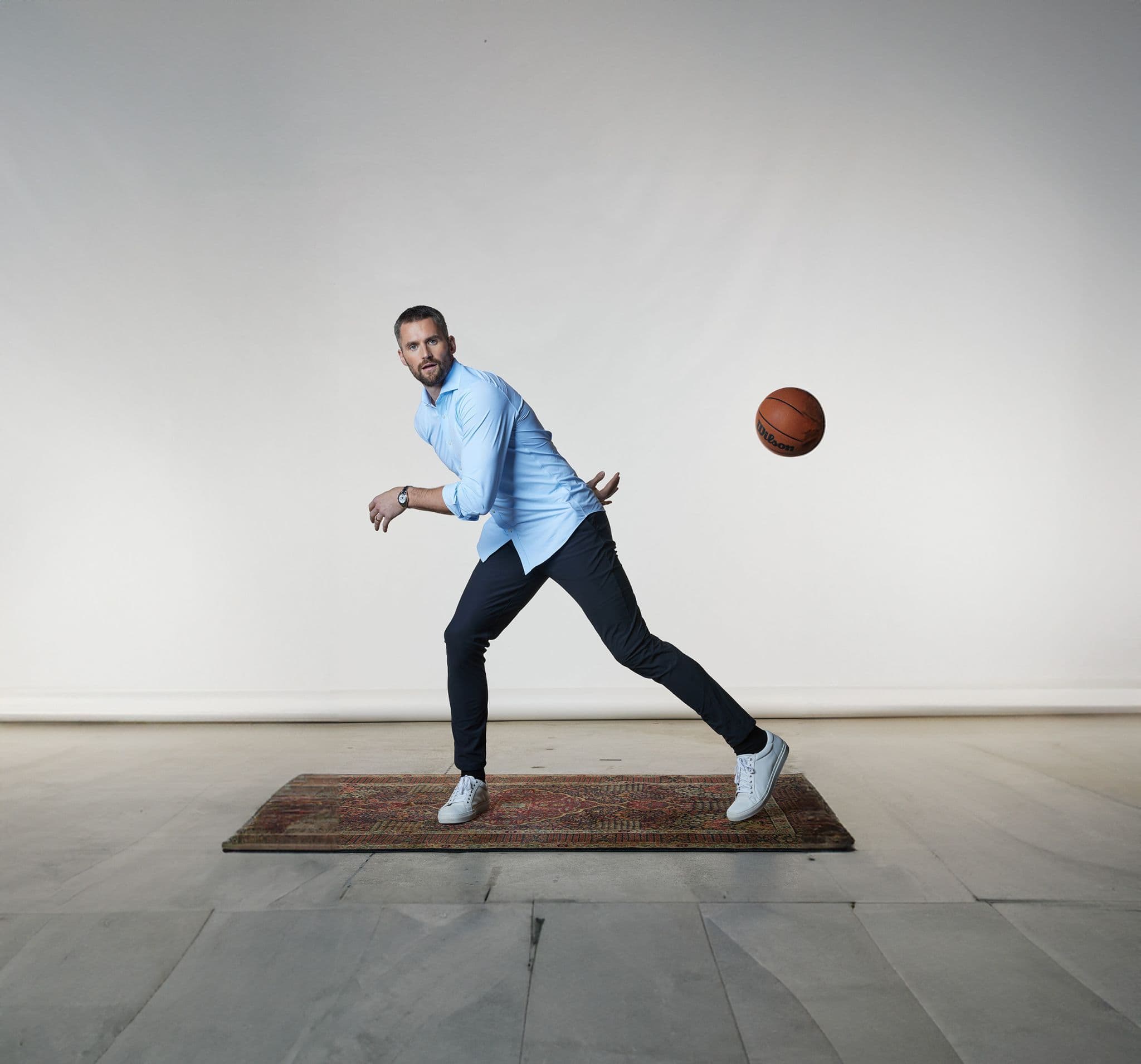A man practicing basketball moves on a small rectangular mat.