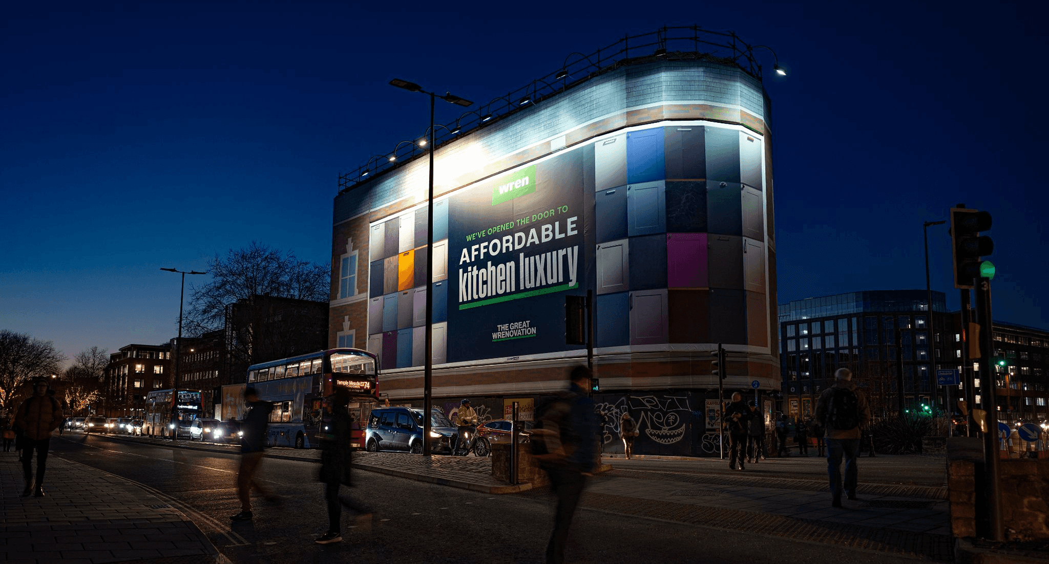 Large colorful Wren Kitchens digital billboard illuminated at night in a city setting.