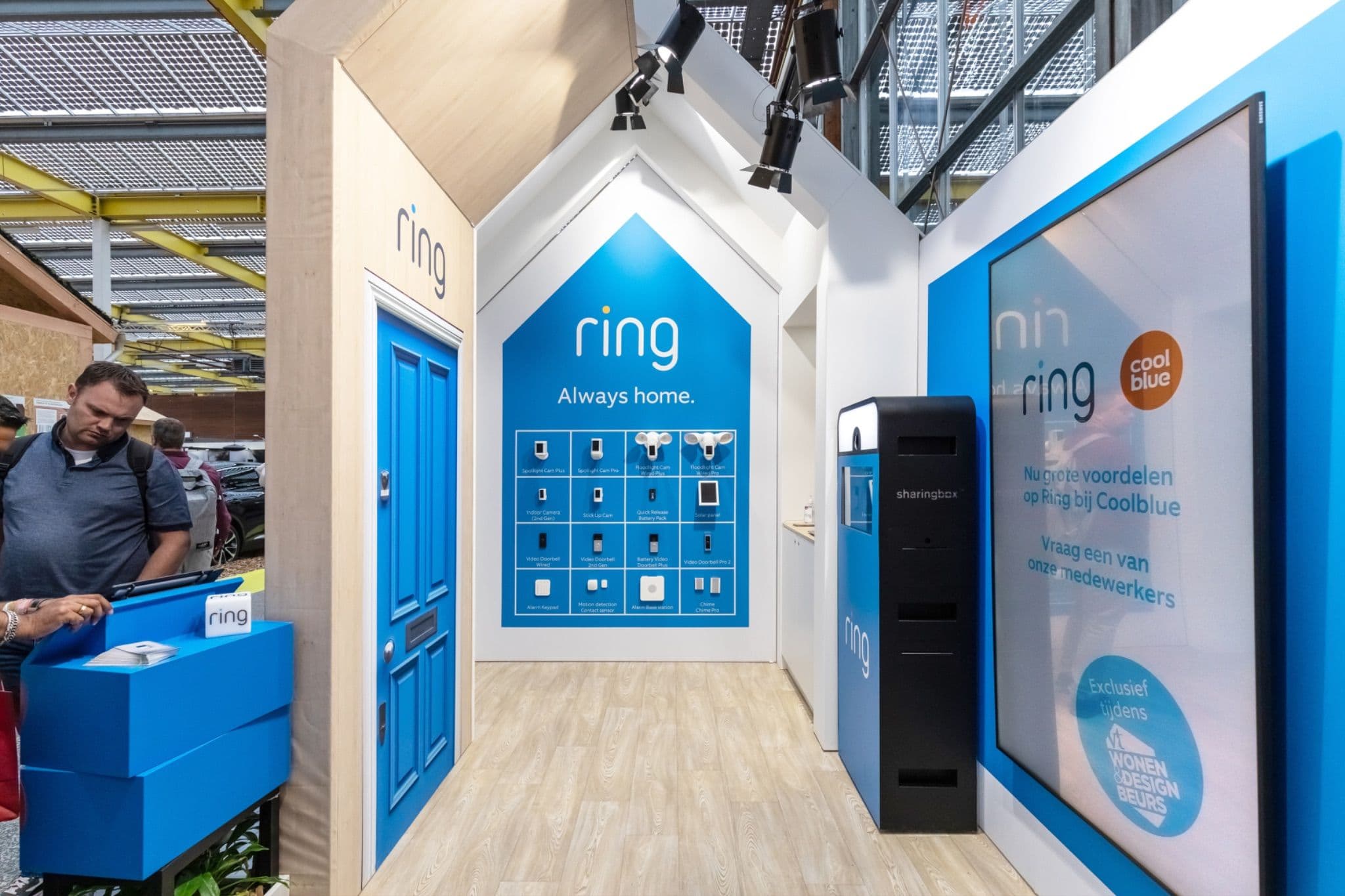 Ring trade show stand featuring a blue door, product wall, and digital signage with Coolblue branding.