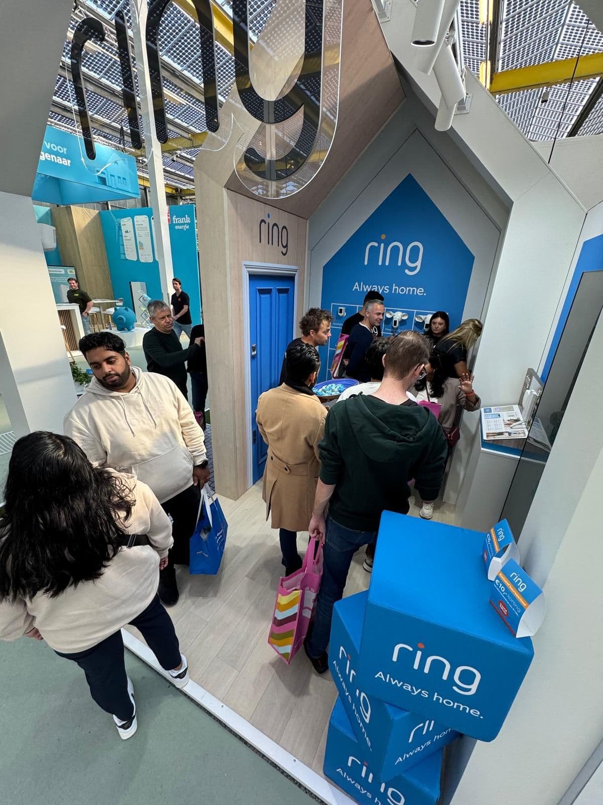 High-angle view of a crowded Ring event activation with attendees browsing smart home security products.