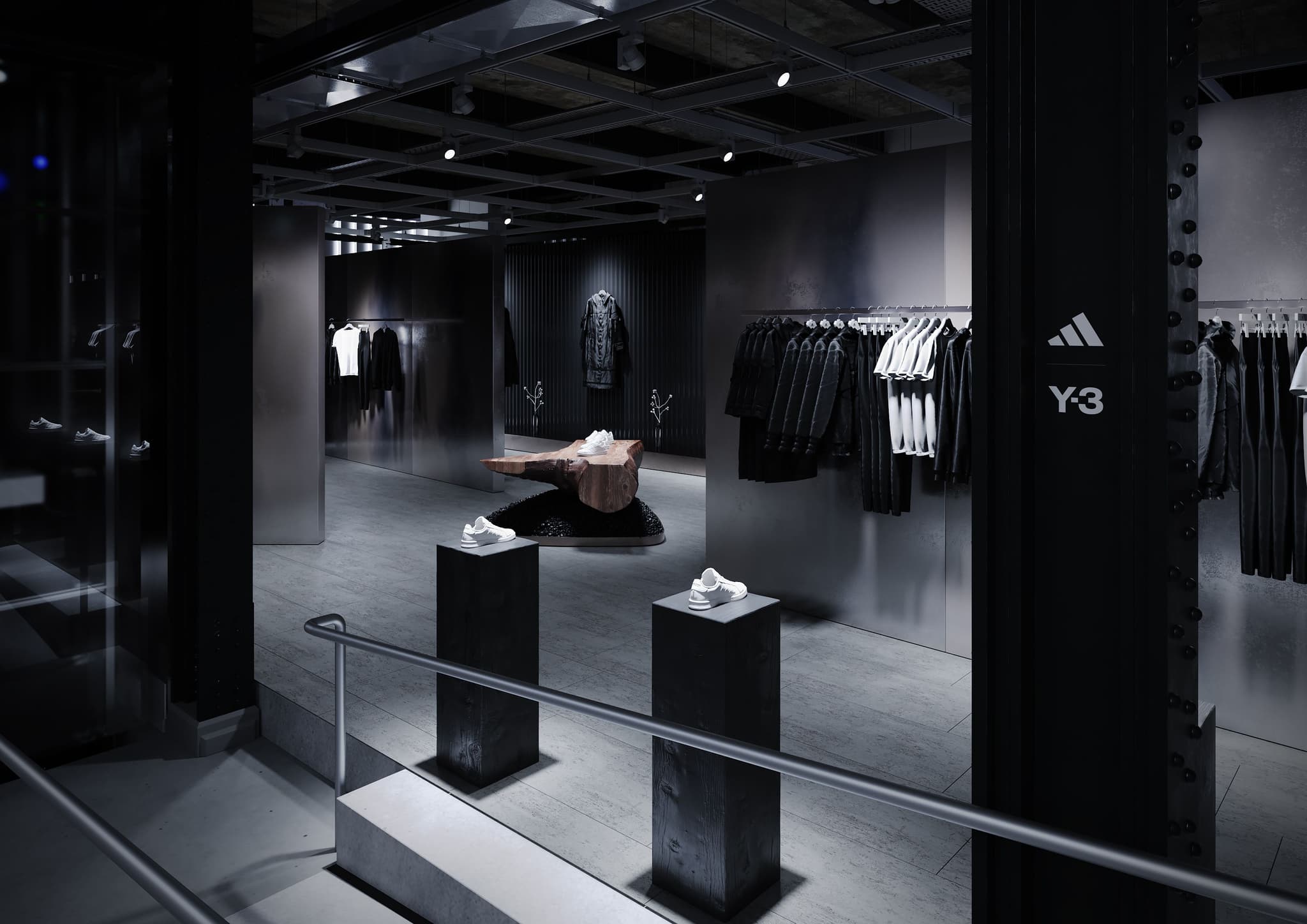 Accessible ramp entrance into a dark, industrial Y-3 retail space featuring metal clothing racks and sneaker displays.