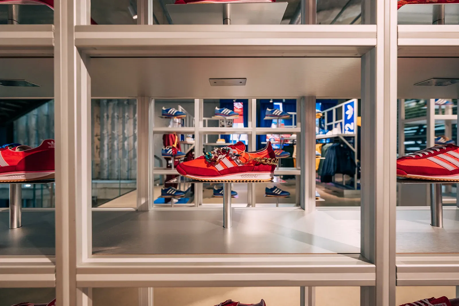 Red Adidas SL 72 sneaker displayed on a shelf, customized with a gold chain and colorful charms.
