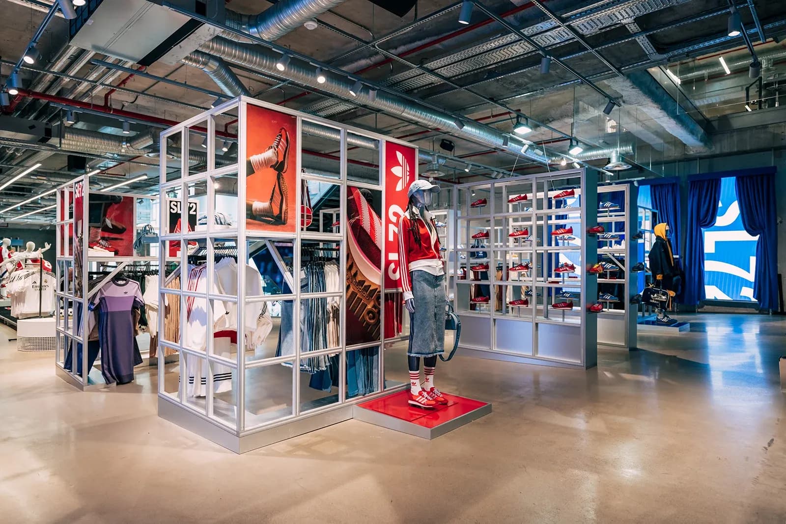 Interior of an Adidas store featuring SL 72 sneaker displays on white grid shelves and a mannequin in red sportswear.