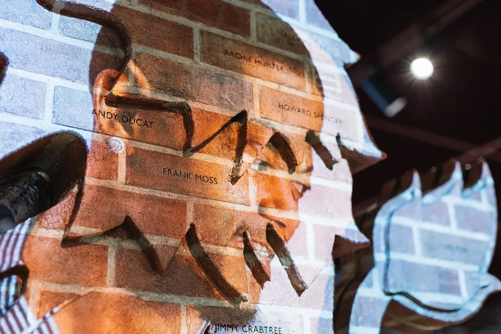 Close-up detail of the brick lion sculpture showing engraved names of historical players like Frank Moss and Andy Ducat.
