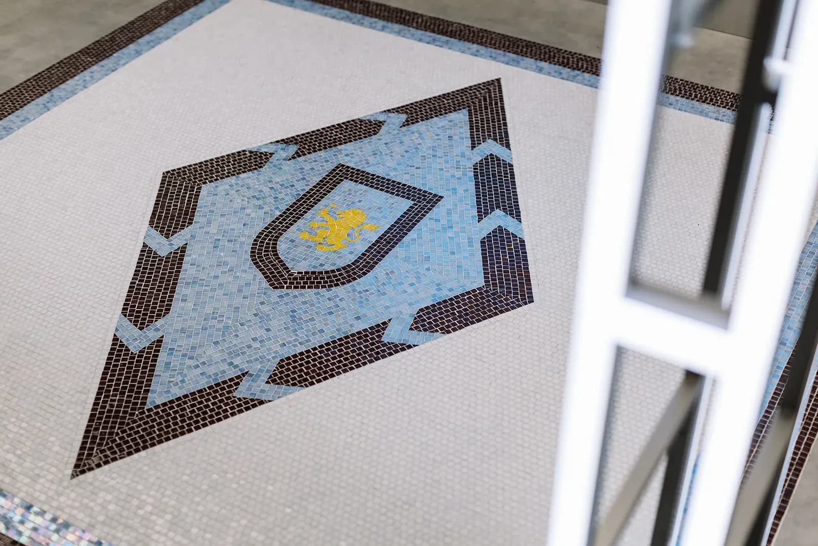 Detailed mosaic floor tile featuring the yellow Aston Villa lion crest inside a blue diamond pattern.