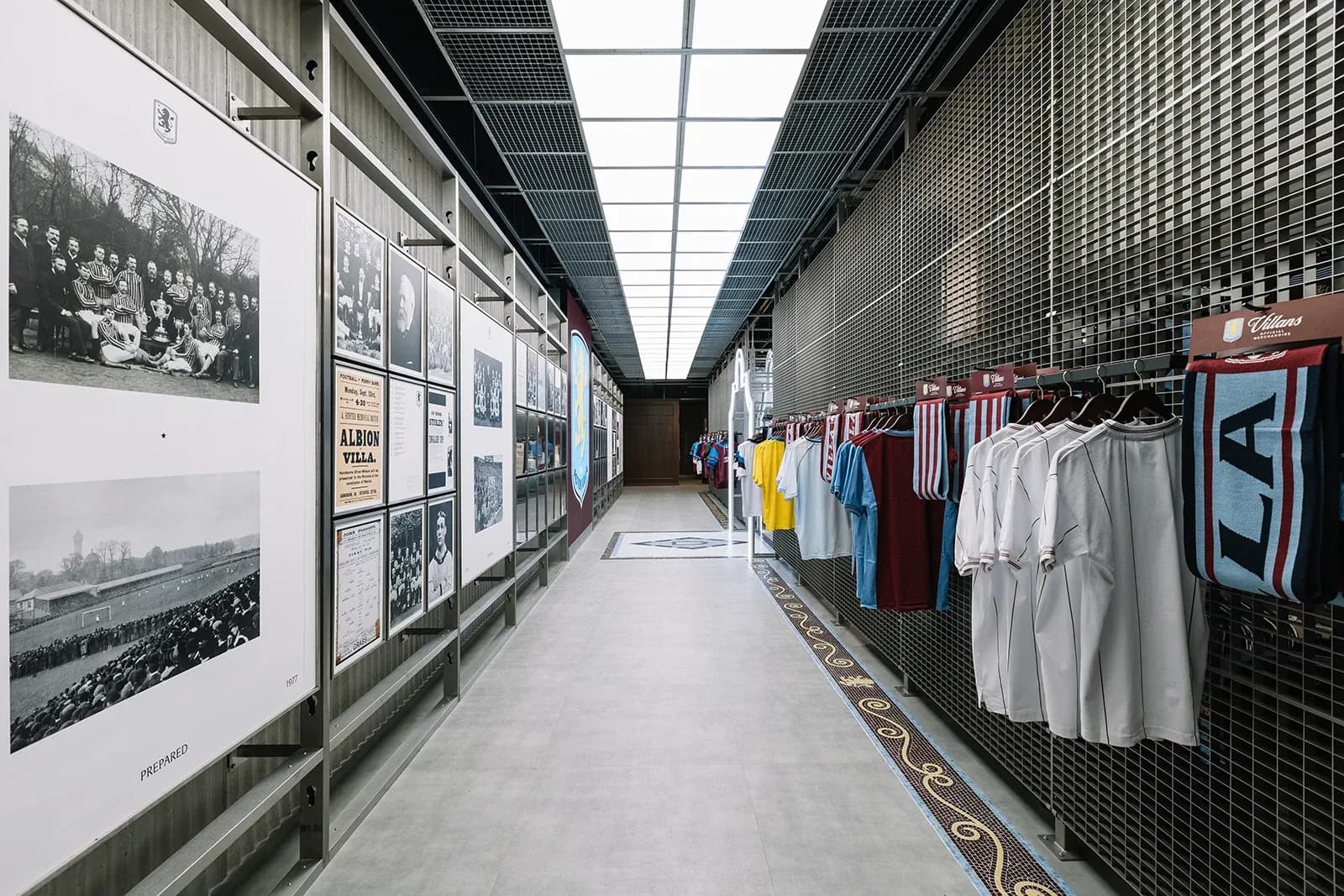 Hallway inside Aston Villa store featuring a wall of historical black and white team photos and hanging merchandise.