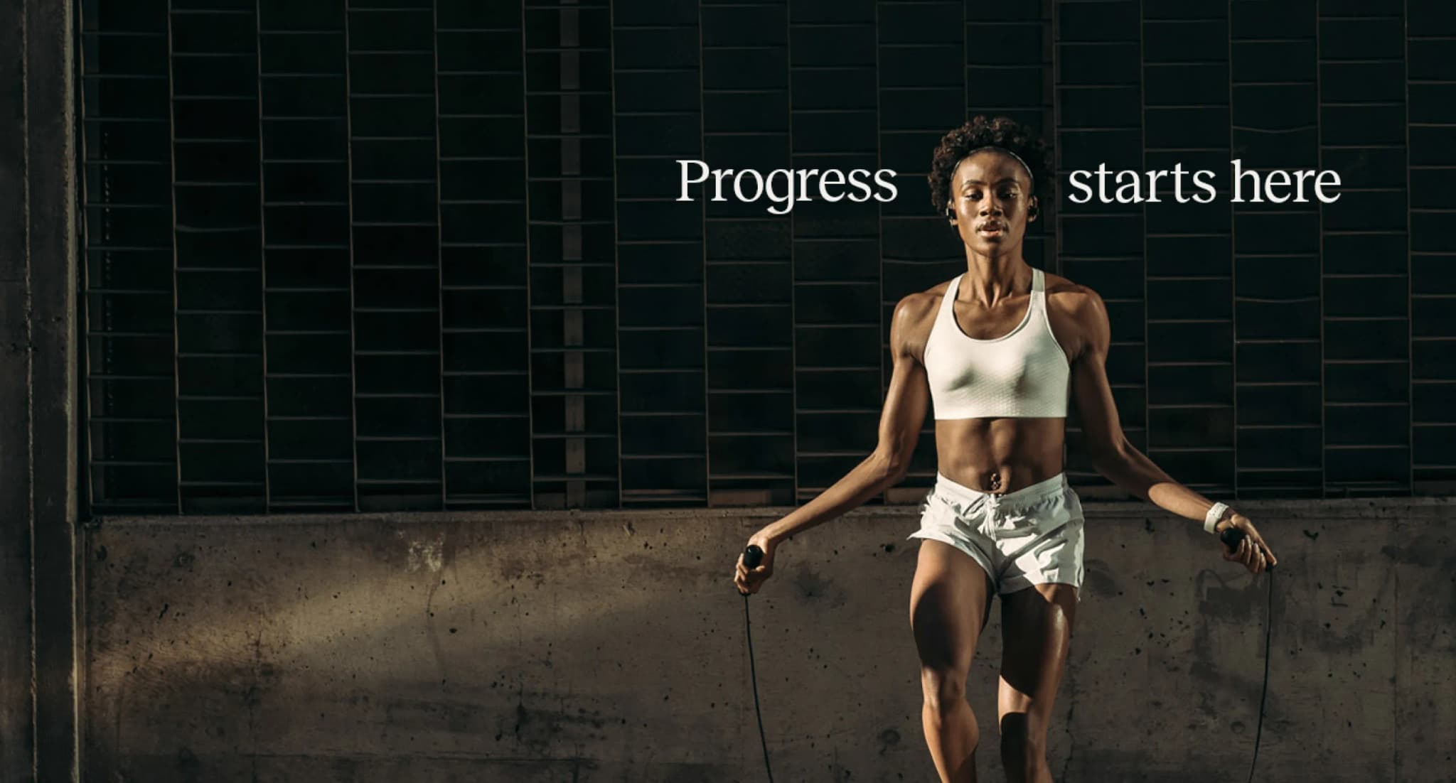 A woman jumping rope in athletic wear with the text "Progress starts here."