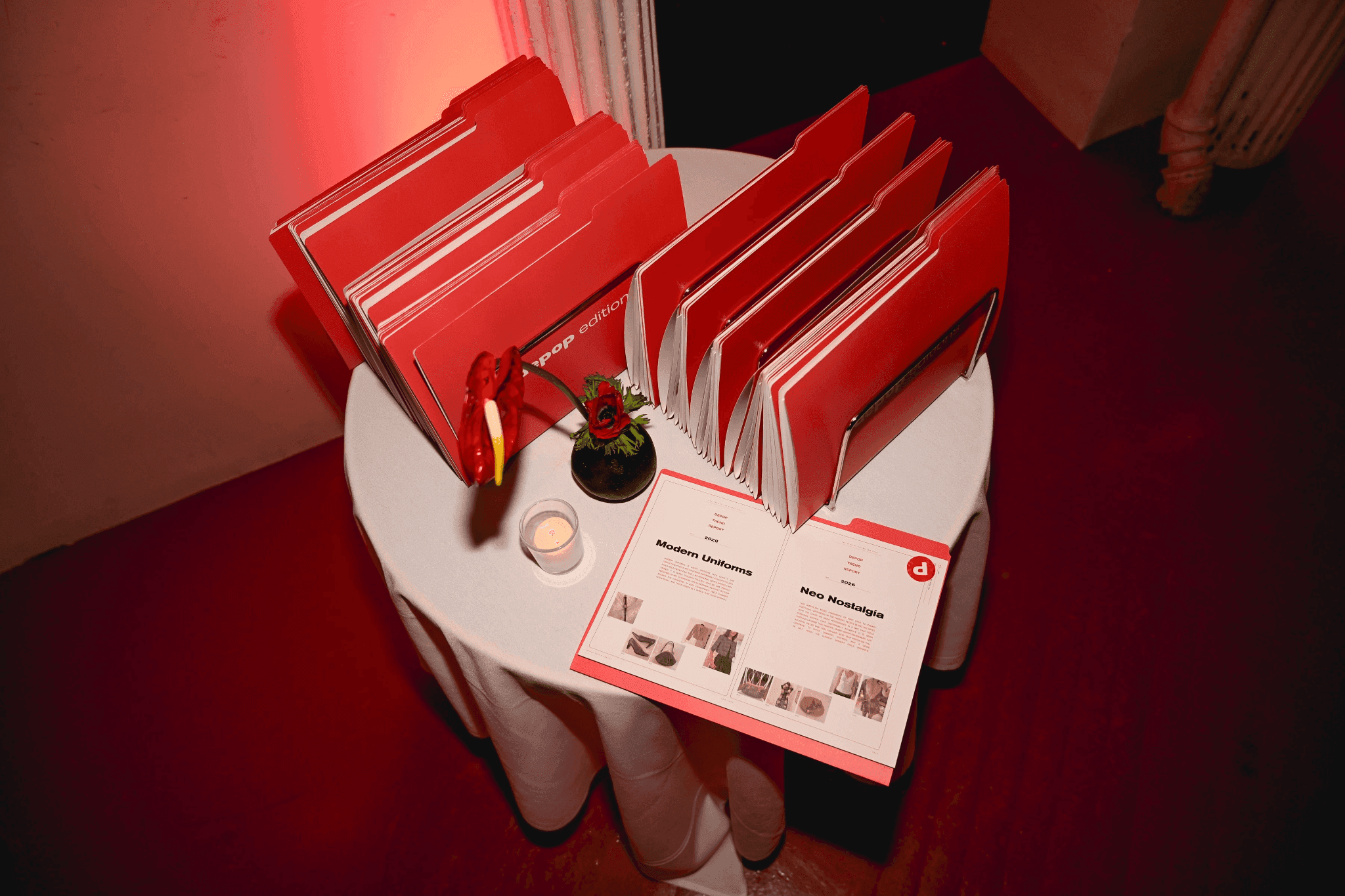 Stack of red Depop Editions mini Trend Report booklets on a display table for guests.
