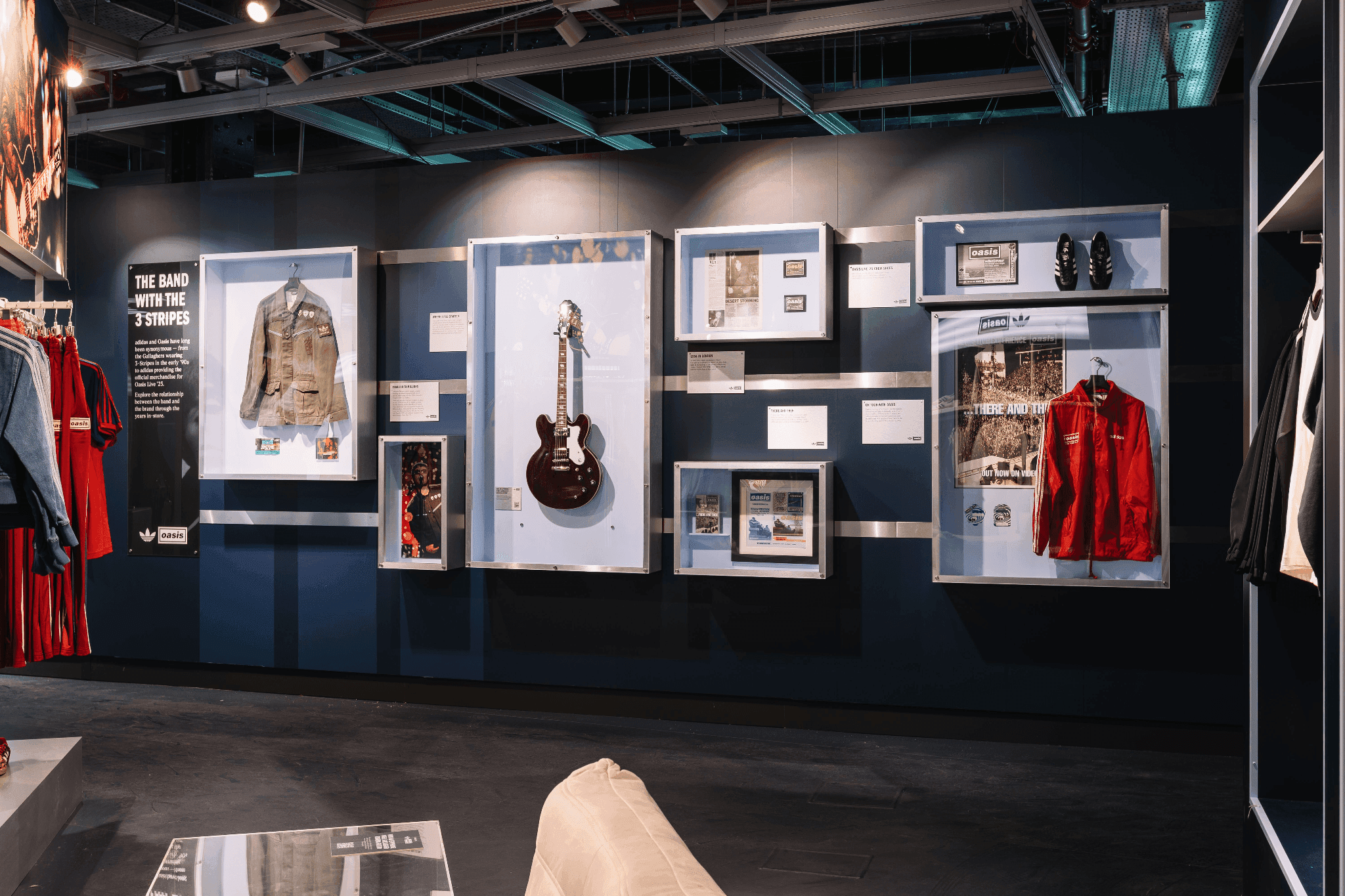 A black wall featuring framed musical instruments and vintage jackets as part of an in-store exhibit.